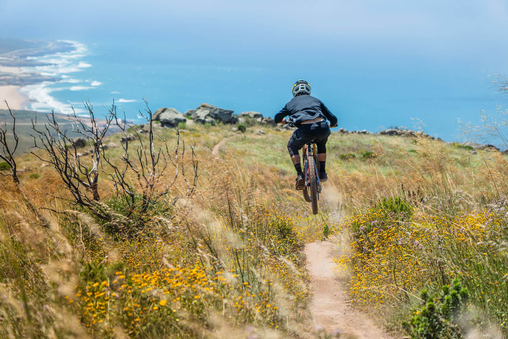 Mountain bike rider flying down a trail in the Sintra mountains with the sea in the background during a group ride