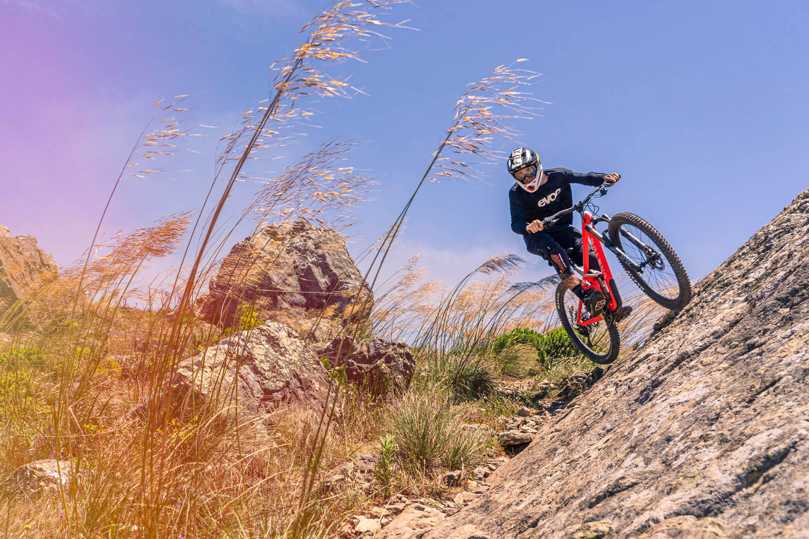 Mountain bike rider doing a wallride on a rock slab in the Sintra mountains during a group tour